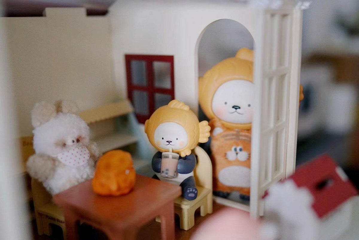 Orange-hooded collectible figures arranged in a cozy miniature dining room display