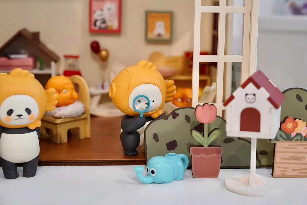 Orange-hooded collectible figures exploring a miniature garden with a magnifying glass