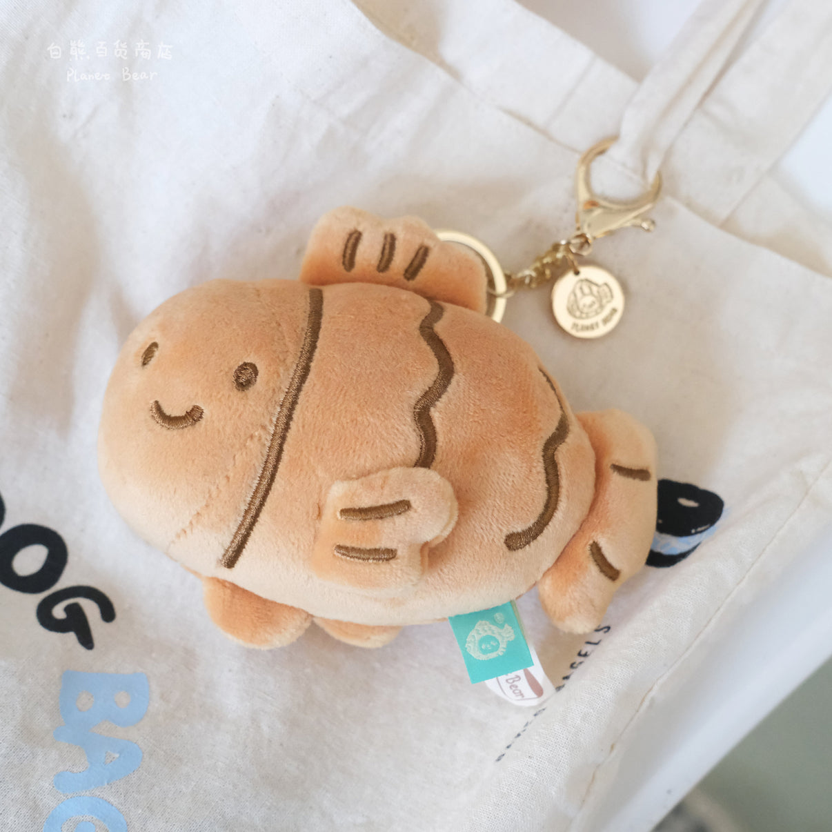 Brown Taiyaki Plush Keychain close-up attached to a canvas bag