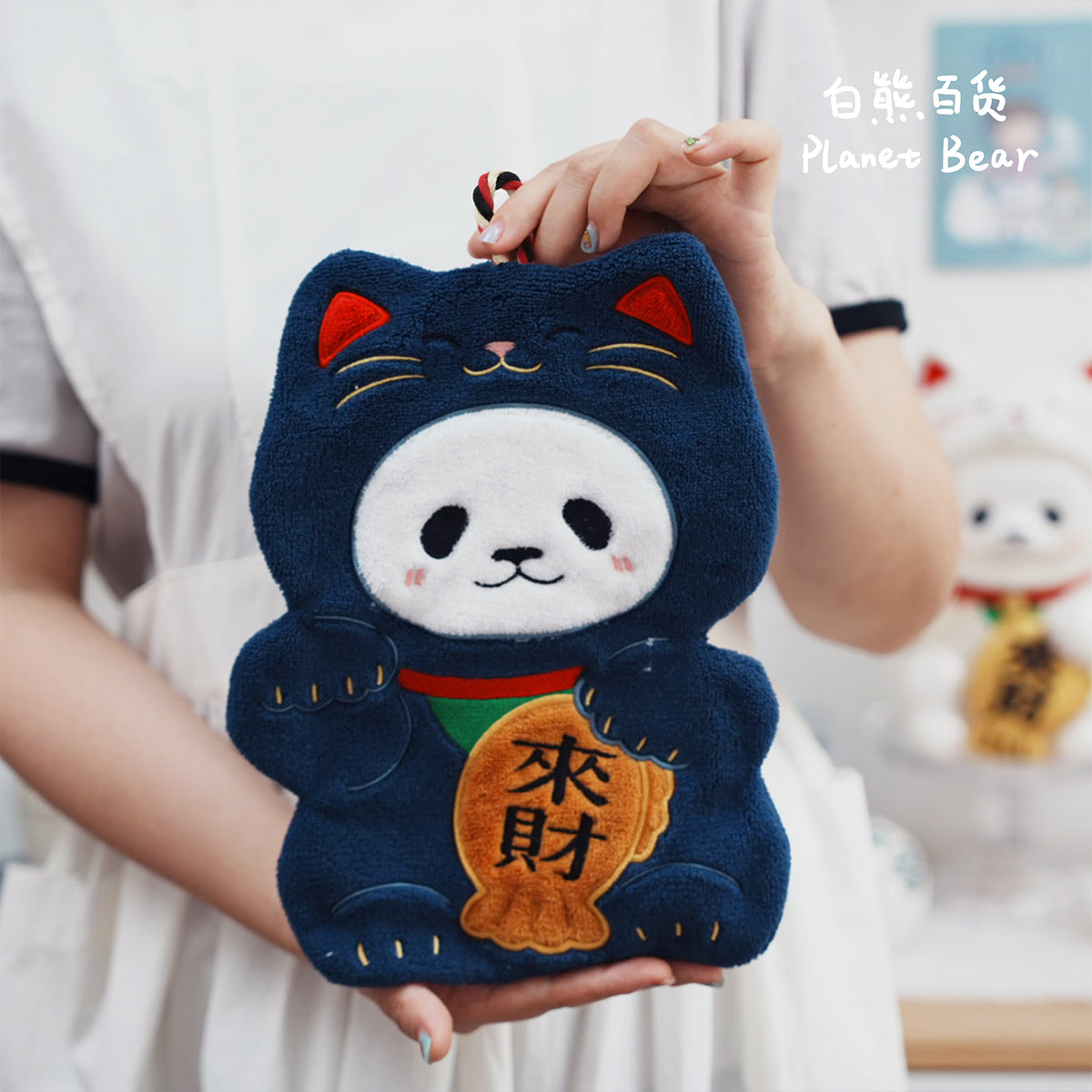 Front view of the navy blue PanPan Super Lucky hanging hand towel held by its braided loop